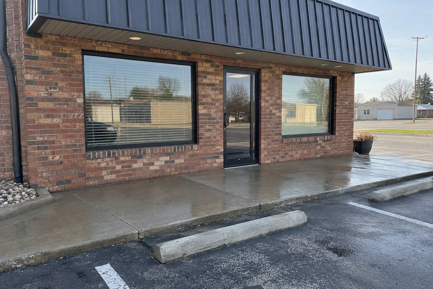Small brick storefront with a rinsed concrete sidewalk