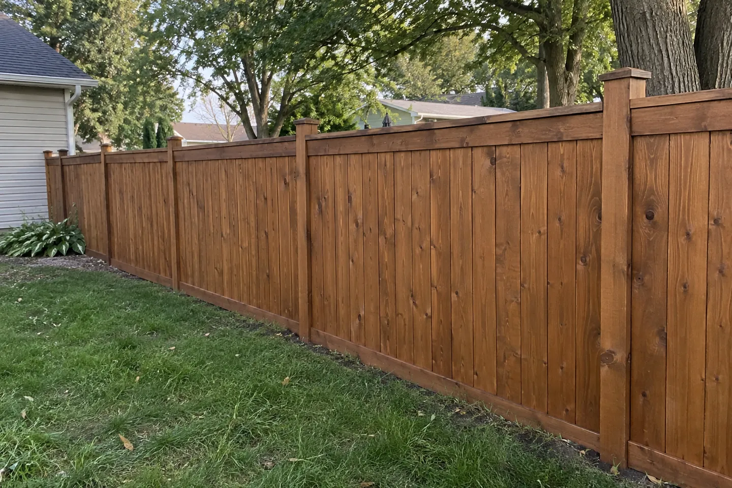 Cedar-brown wooden privacy fence along a backyard lawn
