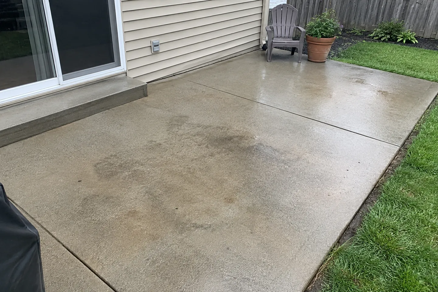 Cleaned concrete patio beside a house and lawn